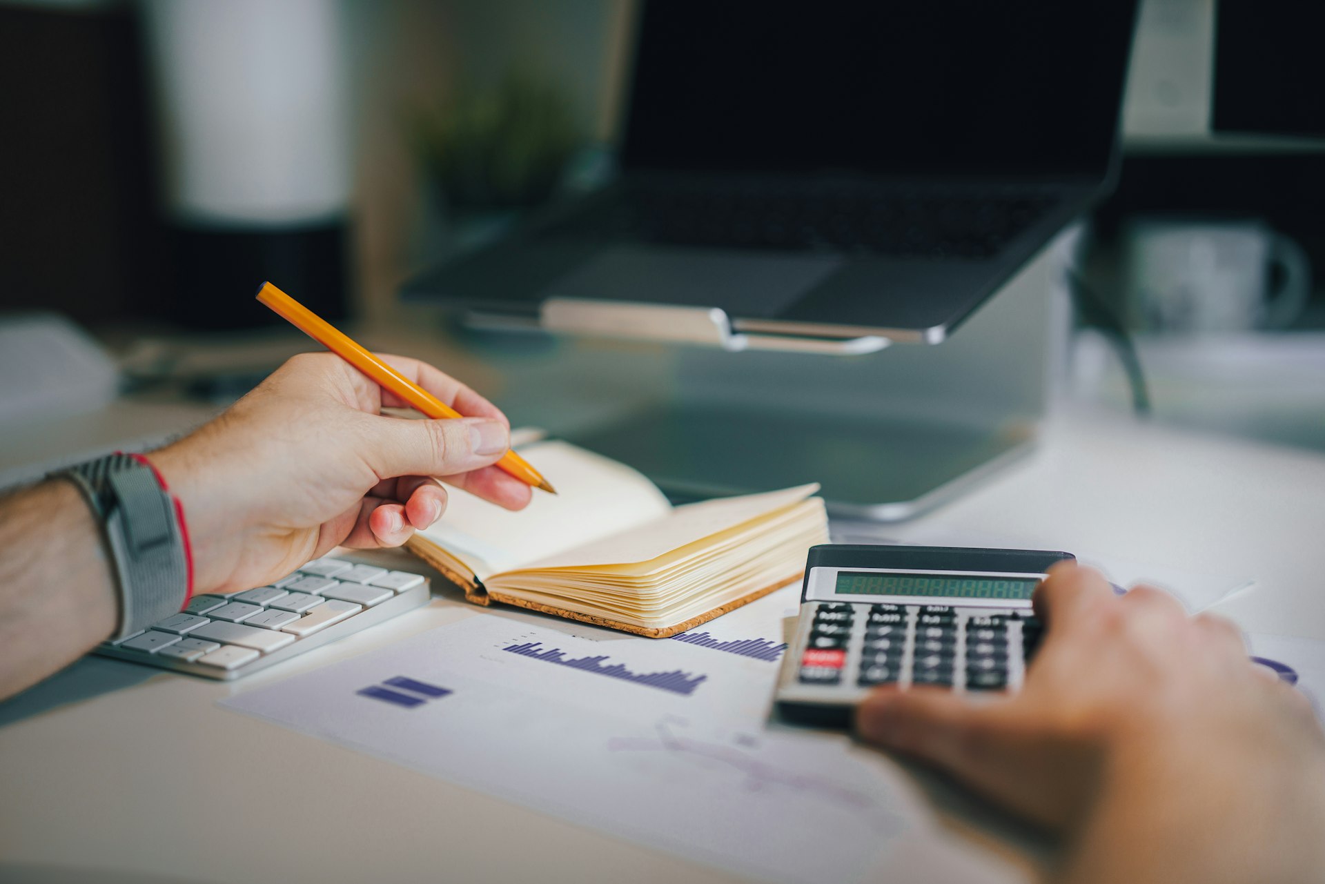 une personne assise à un bureau avec une calculatrice et un carnet